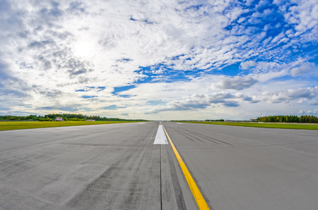 Airport runway to in horizon and picturesque clouds in the blue skyの写真素材