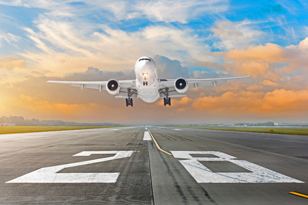 Airplane flying deperture landing speed motion on a runway in the evening during a bright red sunsetの写真素材