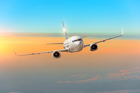 Passanger airplane above the clouds horizon sky with bright sunset colorsの写真素材