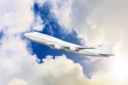 Airplane flies in the clouds with the divine shining of the sun. The concept of safe flightsの写真素材