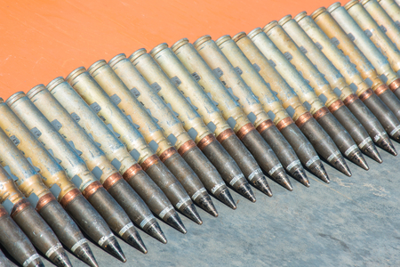Number of cartridges from machine gun folded in a row on a orange backgroundの写真素材
