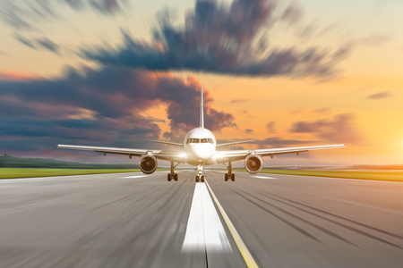 Commercial airplane accelerates on runway airport at sunset at a speed motion blurの写真素材