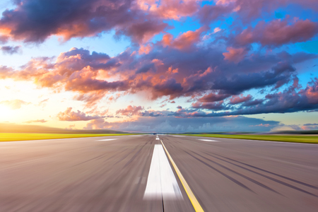 Runway at the airport in the evening sunset sun light bright red cloudsの写真素材