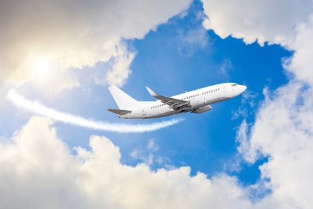 Airplane flies in sky, a journey through the clouds and a sunny glareの写真素材