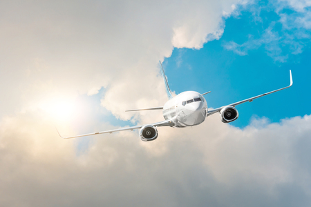 Airplane flies high in the sky, a journey through the clouds and a sunny glareの写真素材