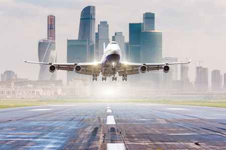 Commercial airplane jetliner approaching for landing on runway, modern city on backgroundの写真素材