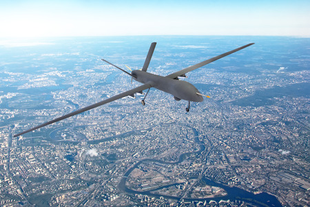 Unmanned military drone patrols the territory, flying over the disrtict of cityの写真素材