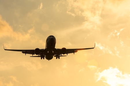 Dark silhouette of an airplane at sunset approach in the airport of a beautiful beautiful skyの写真素材