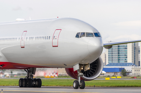 Passenger aircraft on the airport runway, against the backdrop of modern buildings cityの写真素材