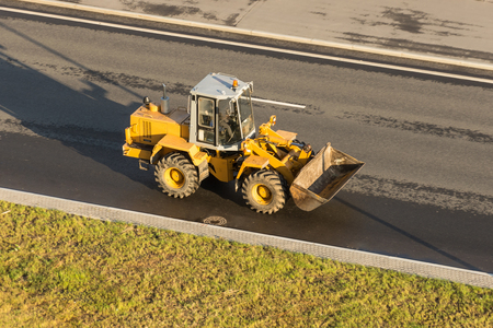 Yellow tractor with a bucket on the highwayの写真素材