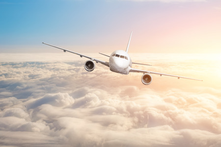 Passenger aircraft flying above the clouds horizon sky with bright sunset colors.の写真素材