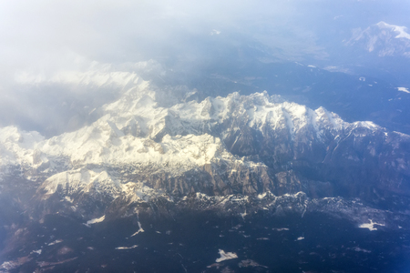 Mountains with snow-capped peaks top from the height of the aircraftの写真素材