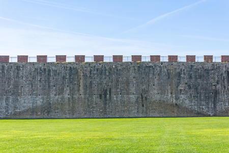 High brick wall fortress, on the foreground green grass lawnの写真素材