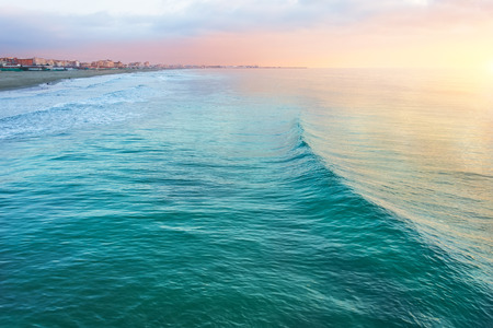 View of the coastal strip of the beach and big waves, evening at sunset