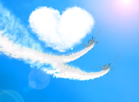 Two airplanes as a loving couple in love fly around a cloud of heartsの写真素材