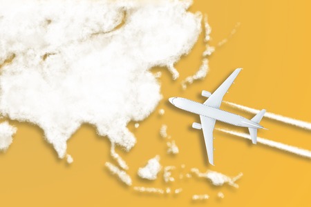 Model airplane design miniature yellow background fluffy clouds in the shape of continent Asia. The...