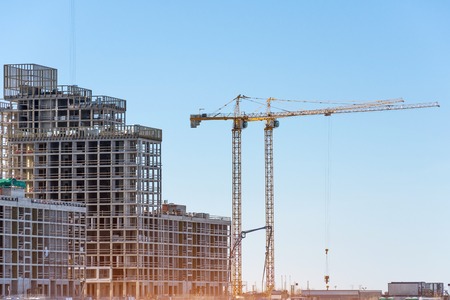 View of a residential complex under construction with high cranes. Large-scale building of the city.