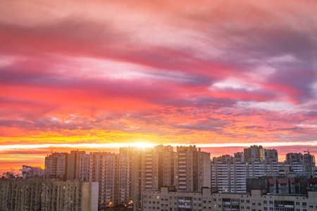 Bright sunrise red pink clouds on residential high-rise buildings on the horizonの写真素材