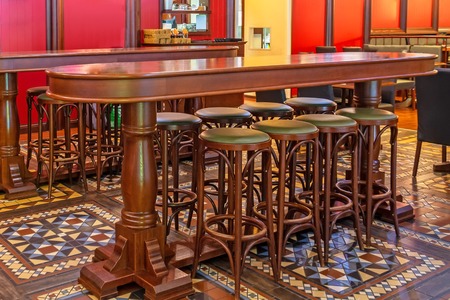 Row of wooden high chairs in a bar in front of a table in a pubの写真素材