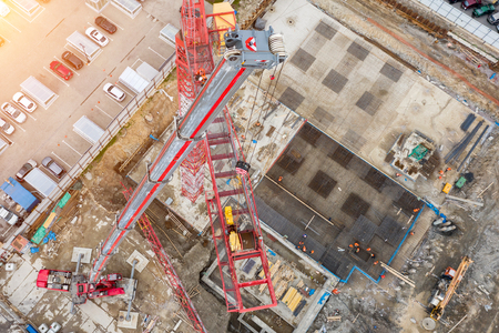 Installation of a construction crane, with the help of a crane on a truck, aerial top view of the pit and building site, the foundationの写真素材