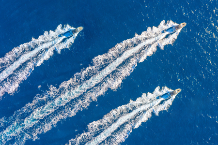 Three speed boats launch at high speed floats in the ocean, aerial top viewの写真素材