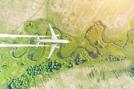 Airplane flies gaining height against the background of the aerial landscape earth's surface, below river, meadow fields, forestsの写真素材