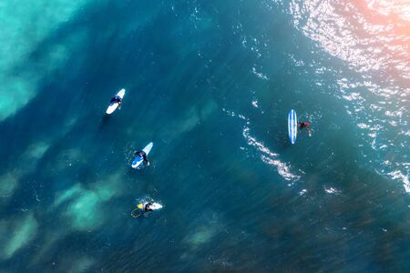Surfers on the water in the bay in anticipation of a big wave, aerial top view
