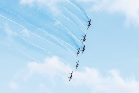 Group of fighters in the blue sky with a trace of black smoke and traces of white vapor vortex cloudsの写真素材