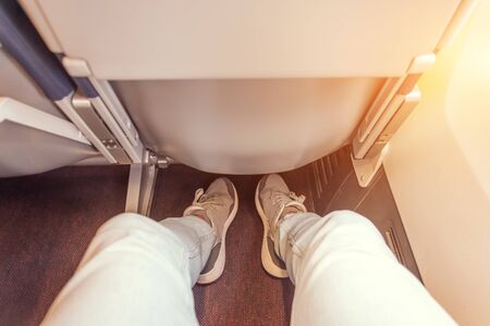 Enough legroom between the seats in the passenger plane, the view of the men's legs. Comfortable flight free space plusの写真素材