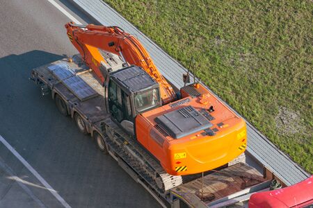 Truck with a long trailer platform for transporting heavy machinery, loaded excavator. Highway transportationの写真素材