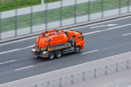 Truck with orange water tank rides on the highway