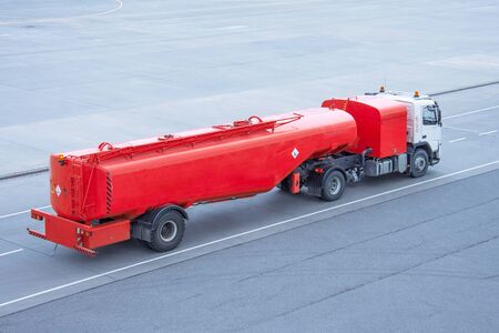 Red truck with a tank and a trailer of aviation fuel on the airport airfield