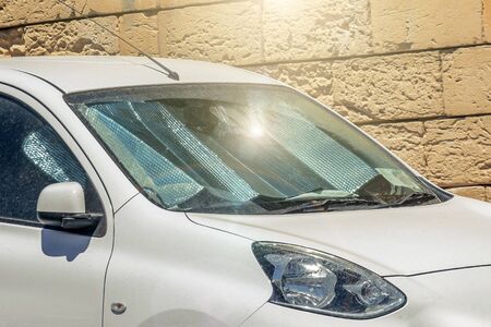 Protective reflective surface under the windshield of the passenger white car parked on a hot day, sun rays protection and heating vehicle interior.の写真素材