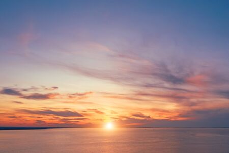 Skyline with a bright sunset in warm colors and picturesque high clouds over the bay, aerial view