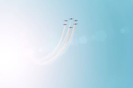 Group of fighter jets flying against a bright blue sky, performing figures from the smoke