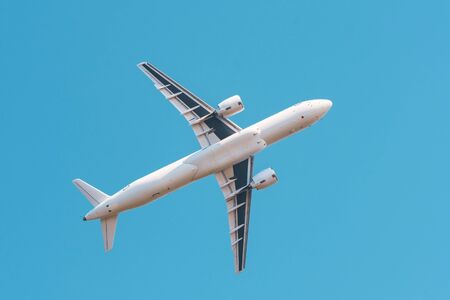 Airplane flies high in the clear sky, bottom viewの写真素材