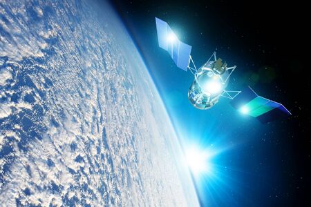 Space satellite orbiting the earth during sunset and bright rays lights sun reflected from solar...