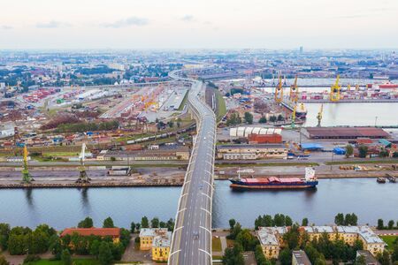 Freeway over the industrial area of the city and the sea channel, aerial top view