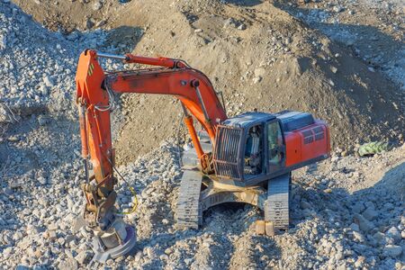 Excavator with a magnetic installation on the boom, at the site of the demolition of the building