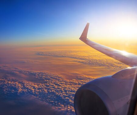 Scenic clouds at sunrise from an airplane, view of the engine and wingの写真素材