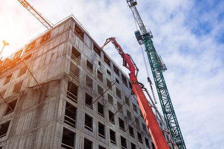 Pouring concrete to the upper floors of a building under construction with the help of an arrow of a...