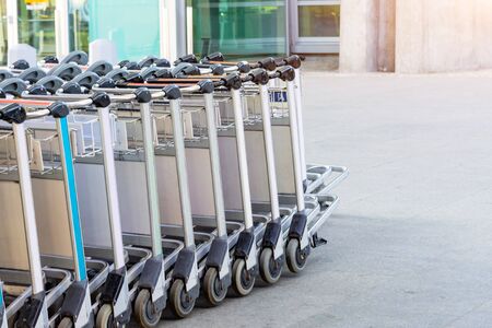 A row of passenger luggage trolleys at the entrance to the airport terminal buildingの写真素材