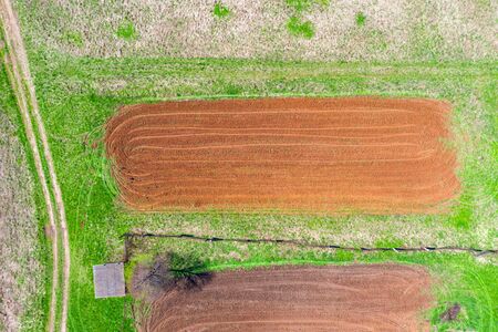 Small empty field in the village before planting vegetables, fence and barn. Aerial height view