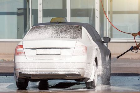 The car covered with foam from the gun for application to the express car washの写真素材