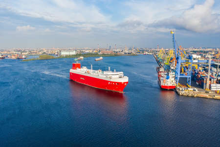 Cargo red ship for the transport of cars and other new transport sails from the port to the sea