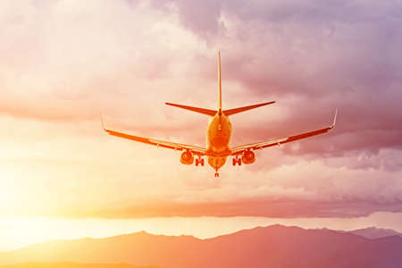 Airplane landing approach against the background of mountains and a bright sunset