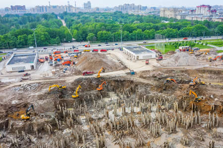 Working excavators on the site of a demolished building. Construction of a huge building in a pit near the city park cityscape, aerial top viewの写真素材