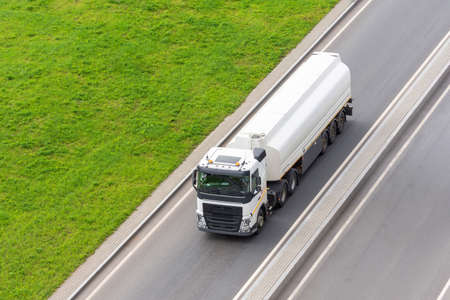 Fuel truck driving on the road next to the grassの写真素材