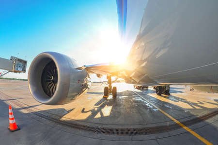 Bright sun over the wing and engine of an airplane at the airport