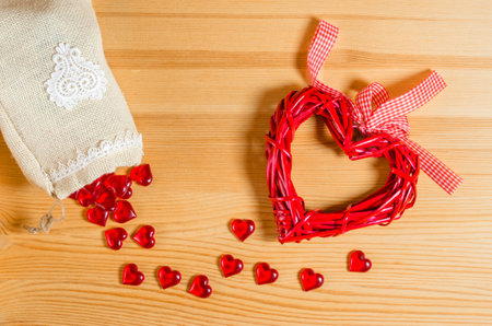 Linen bag with scattered hearts, wicker heart with a flying bag on a wooden table